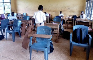 Students who sit in plastic chairs write on their laps