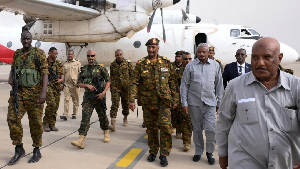 Sudan's military leader, General Abdel Fattah al-Burhan, (M), arrives with officials and guards i
