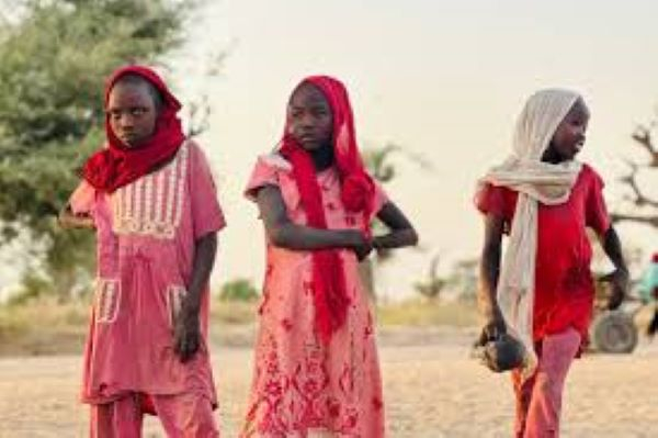 Displaced Sudanese girls, who fled the Zamzam camp, look on as they gather near the town of Tawila