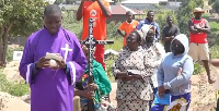 A Catholic priest prays during the burial ceremony of Vanisa Anifa