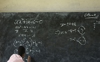 A teacher writing on a blackboard in class