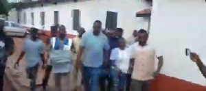 John Dumelo walking side-by-side with the Electoral Officer