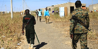 Sudanese security officers patrol as Ethiopian refugees are seen at the Al-Fashaga camp