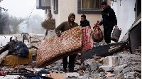 Palestinians carry belongings at the site of an Israeli strike on a house, amid the ongoing conflict
