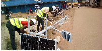 Employees of Geses U Ltd fitting solar street lighting units along the Kabale garage street