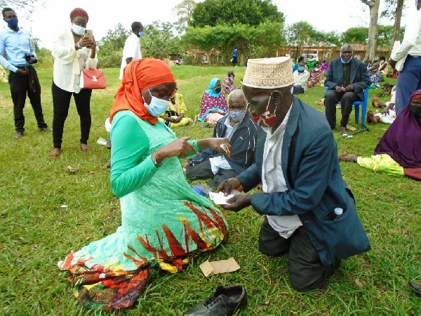 Minister for elderly affairs Sarah Kanyike (left) interacts with a SAGE beneficiary at Kayunga