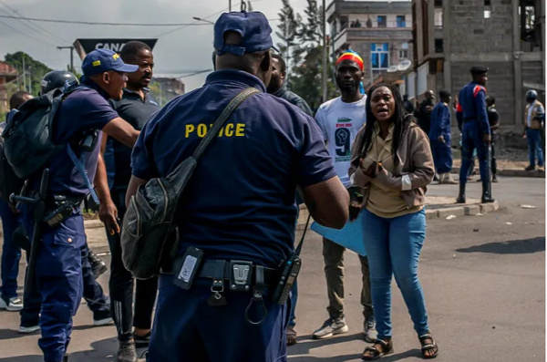 Congolese police talk to demonstrators calling on authorities to enforce an agreed withdrawal of M23