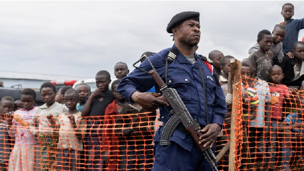 A Congolese police officer stands guard near internally displaced people gathered at  Bushagara site