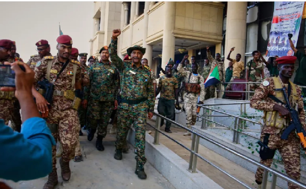Sudan's military chief Abdel Fattah al-Burhan, (C), is greeted by soldiers