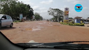 The stretch of road is been taken over by muddy puddles and potholes