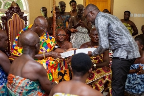 Otumfuo Osei Tutu II receiving the signed documents from Dr Kingsley Agyeman