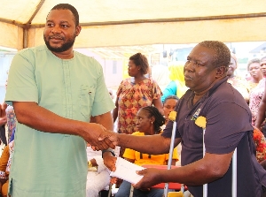 Elijah Adansi-Bonah presents an envelope to one of the victims
