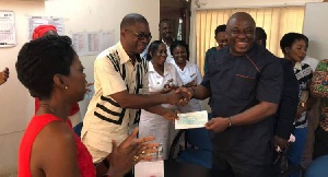 Carlos Ahenkorah presenting the cheque to the Metro Health Director