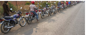 Motorcycle taxi riders queue along the road for customers