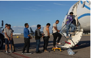 Immigrants board a plane to be deported from the US by Immigration and Customs Enforcement officers