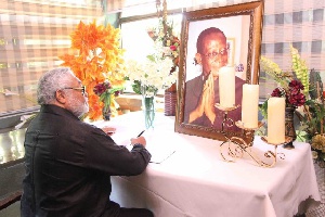 Former President Jerry John Rawlings signing the book of condolence for the late Kwabena Adjei